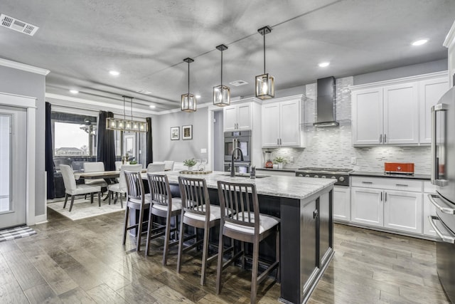 5315 Hammond Cir, Iola, TX 77861 - kitchen with wall chimney exhaust hood, a sink, crown molding, an island with sink, and stainless steel appliances