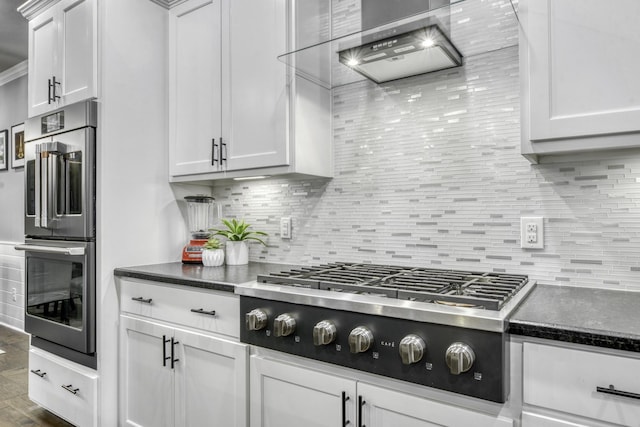 5315 Hammond Cir, Iola, TX 77861 - kitchen featuring appliances with stainless steel finishes, wall chimney exhaust hood, tasteful backsplash, and white cabinetry