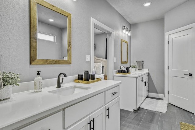 5315 Hammond Cir, Iola, TX 77861 - bathroom featuring two vanities, a textured wall, and recessed lighting