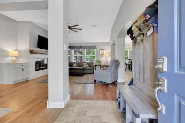 24240 Oak Hollow Blvd, Hockley, TX 77447 - entryway with ceiling fan, a glass covered fireplace, arched walkways, light wood-style flooring, and baseboards
