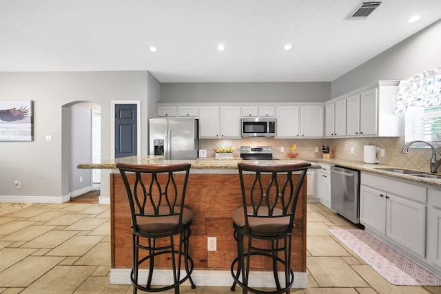 24240 Oak Hollow Blvd, Hockley, TX 77447 - kitchen featuring appliances with stainless steel finishes, a sink, arched walkways, decorative backsplash, and white cabinetry