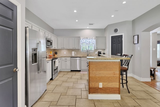 24240 Oak Hollow Blvd, Hockley, TX 77447 - kitchen with stainless steel appliances, backsplash, a breakfast bar, recessed lighting, and a center island