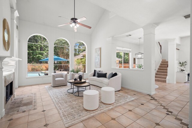 35 Dewdrift Pl, The Woodlands, TX 77382 - tiled living area with ceiling fan, a premium fireplace, high vaulted ceiling, stairway, and decorative columns