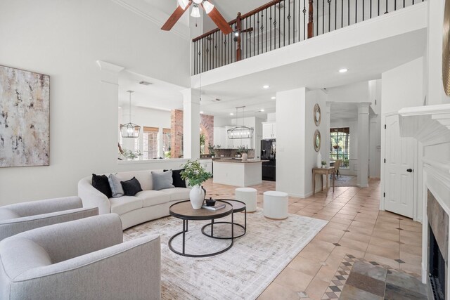 35 Dewdrift Pl, The Woodlands, TX 77382 - living area with ceiling fan, a towering ceiling, light tile patterned flooring, ornate columns, and a tiled fireplace