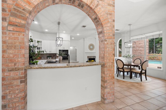 35 Dewdrift Pl, The Woodlands, TX 77382 - kitchen with arched walkways, light tile patterned floors, open shelves, white cabinetry, and recessed lighting