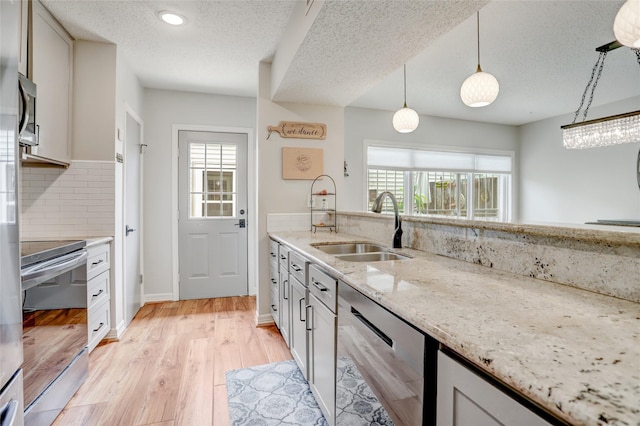 2014 Augusta Dr, Houston, TX 77057 - kitchen featuring stainless steel appliances, a sink, tasteful backsplash, a textured ceiling, and hanging light fixtures