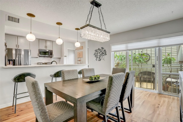 2014 Augusta Dr, Houston, TX 77057 - dining area with a textured ceiling, light wood-type flooring, and a chandelier