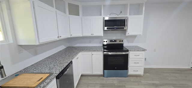 110 Hidden Cir, Coldspring, TX 77331 - kitchen with appliances with stainless steel finishes, white cabinets, light wood finished floors, and light stone counters