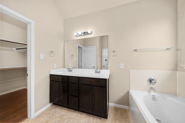 25426 Saddlebrook Champion Way, Tomball, TX 77375 - bathroom featuring double vanity, a garden tub, baseboards, vaulted ceiling, and a spacious closet