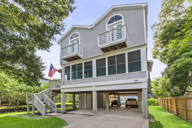 718 Pine Rd, Clear Lake Shores, TX 77565 - view of front of house with a carport, a balcony, a sunroom, driveway, and stairway