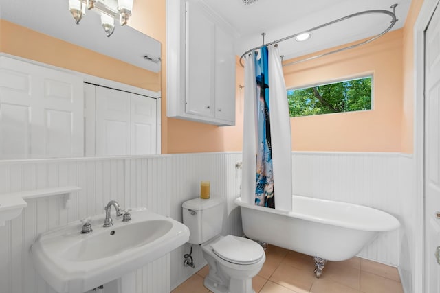 718 Pine Rd, Clear Lake Shores, TX 77565 - bathroom featuring a sink, wainscoting, a freestanding bath, tile patterned floors, and toilet