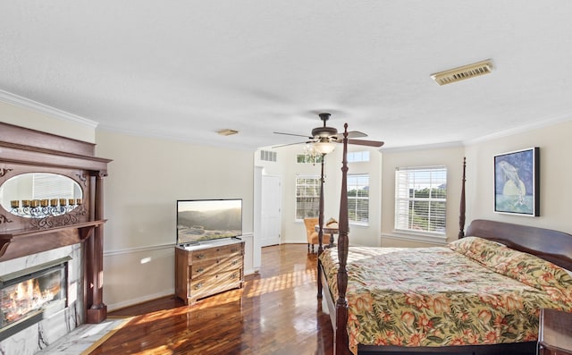 718 Pine Rd, Clear Lake Shores, TX 77565 - bedroom featuring crown molding, wood finished floors, a premium fireplace, a textured ceiling, and a ceiling fan