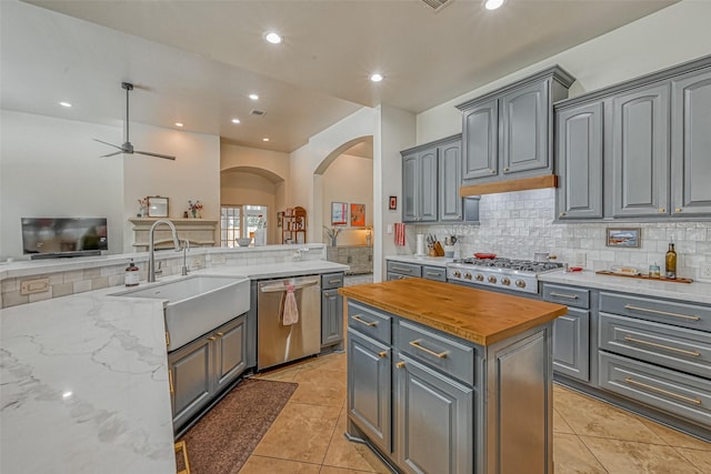 5918 Emmit Creek Ln, Sugar Land, TX 77479 - kitchen featuring stainless steel dishwasher, a sink, gray cabinets, arched walkways, and gas stovetop