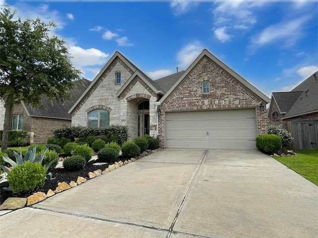 2023 Deer Vly, Missouri City, TX 77459 - french country style house featuring driveway, a garage, brick siding, a shingled roof, and stone siding