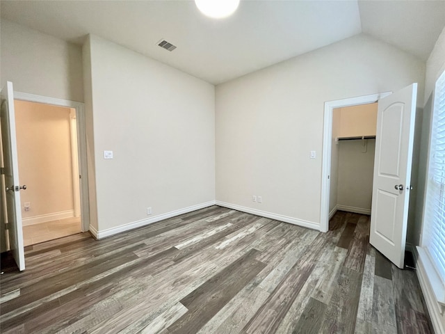 2023 Deer Vly, Missouri City, TX 77459 - unfurnished bedroom with wood finished floors, a closet, lofted ceiling, a walk in closet, and baseboards