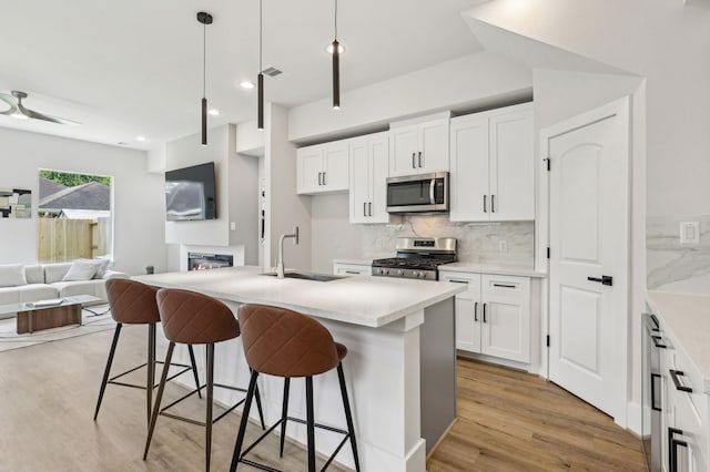 3722 Nathaniel Brown St, Houston, TX 77021 - kitchen featuring stainless steel appliances, a sink, open floor plan, light wood finished floors, and tasteful backsplash