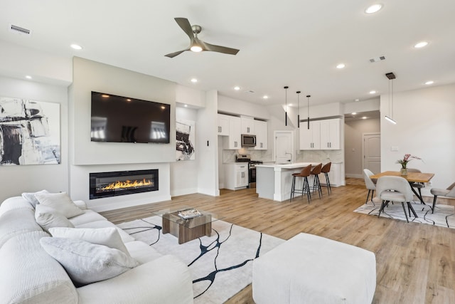 3722 Nathaniel Brown St, Houston, TX 77021 - living area with light wood-style floors, a glass covered fireplace, a ceiling fan, recessed lighting, and baseboards