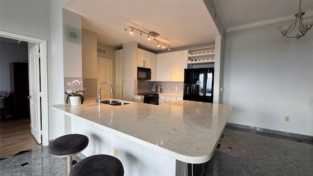 3505 Sage Rd Unit 2405, Houston, TX 77056 - kitchen with black appliances, a sink, a peninsula, ornamental molding, and light stone counters