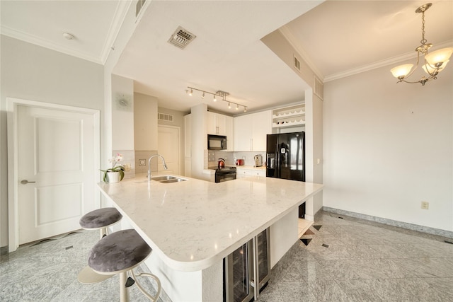 3505 Sage Rd Unit 2405, Houston, TX 77056 - kitchen featuring black appliances, a breakfast bar, a peninsula, light stone counters, and crown molding