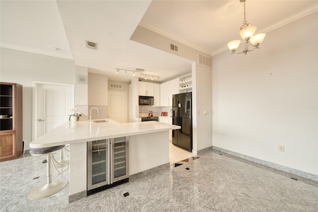 3505 Sage Rd Unit 2405, Houston, TX 77056 - kitchen with wine cooler, black appliances, a peninsula, granite floors, and a chandelier