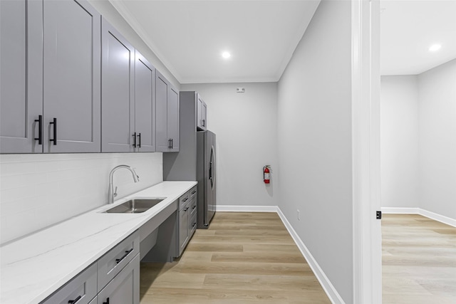 1325 Main St Unit 1103, Katy, TX 77494 - kitchen featuring a sink, stainless steel fridge, gray cabinetry, light wood-type flooring, and light stone counters