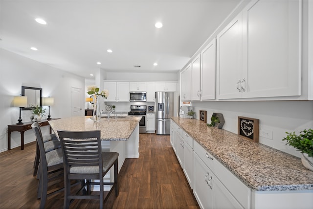 3313 Cold Swan Ct, Conroe, TX 77301 - kitchen with stainless steel appliances, dark wood-style flooring, recessed lighting, white cabinetry, and a center island with sink