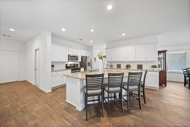 3313 Cold Swan Ct, Conroe, TX 77301 - kitchen with stainless steel appliances, an island with sink, dark wood-style flooring, a breakfast bar area, and recessed lighting