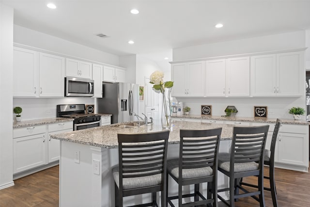 3313 Cold Swan Ct, Conroe, TX 77301 - kitchen with stainless steel appliances, recessed lighting, white cabinetry, a kitchen island with sink, and a breakfast bar