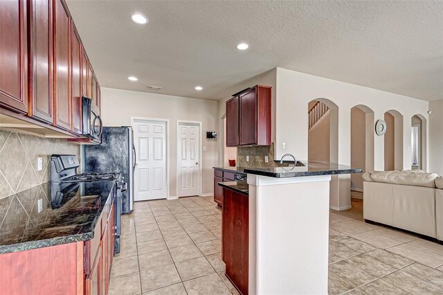 15131 Live Oak Bend Way, Cypress, TX 77429 - kitchen featuring gas stove, reddish brown cabinets, stainless steel microwave, light tile patterned floors, and recessed lighting