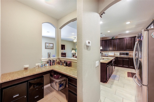 9710 Wild Orange Ct, Spring, TX 77379 - kitchen with stainless steel appliances, arched walkways, a ceiling fan, light stone countertops, and dark brown cabinets
