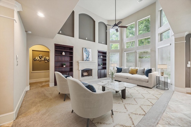 14603 Hampton Green Ln, Houston, TX 77044 - living area featuring built in shelves, a towering ceiling, a ceiling fan, baseboards, and a fireplace with raised hearth