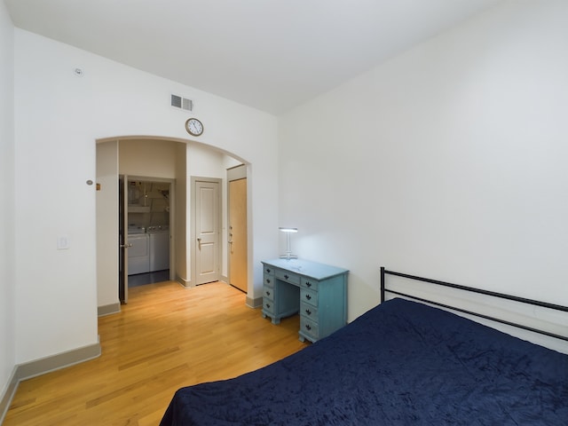 1901 Post Oak Blvd Unit 2215, Houston, TX 77056 - unfurnished bedroom featuring washer and clothes dryer, light wood finished floors, arched walkways, and baseboards