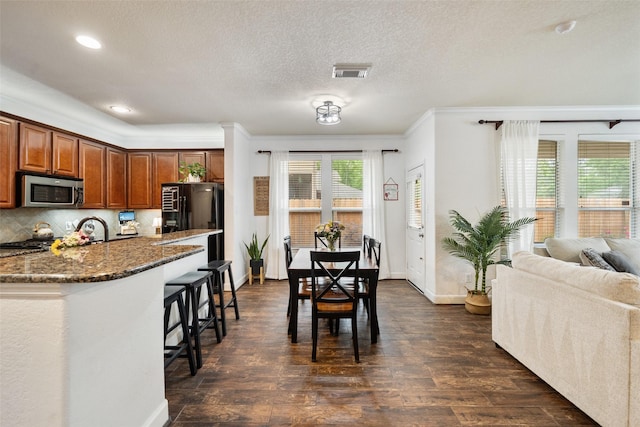 31318 Evergreen Park Ln, Conroe, TX 77385 - kitchen with stainless steel microwave, a breakfast bar, dark stone counters, baseboards, and a textured ceiling