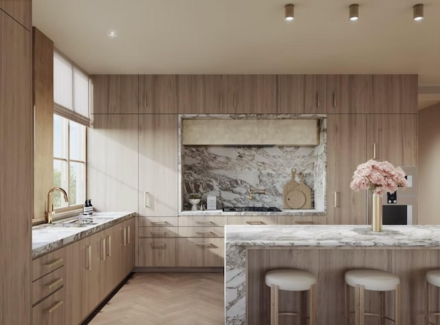 2360 Rice Blvd Unit 701, Houston, TX 77005 - kitchen featuring light stone counters, a kitchen bar, modern cabinets, a sink, and gas cooktop