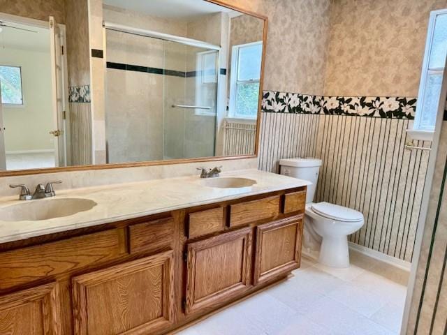 15326 Lindita Dr, Houston, TX 77083 - bathroom featuring wallpapered walls, a shower stall, double vanity, toilet, and baseboards