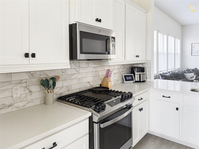 31334 Balsam Hawk Ln, Hockley, TX 77447 - kitchen with stainless steel appliances, light countertops, white cabinetry, and decorative backsplash