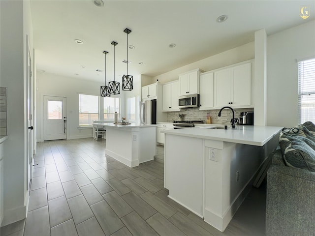 31334 Balsam Hawk Ln, Hockley, TX 77447 - kitchen featuring stainless steel appliances, a sink, a center island, decorative backsplash, and healthy amount of natural light