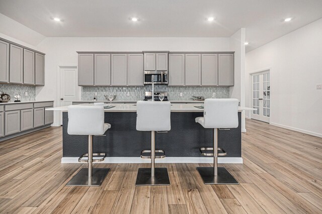 705 Western Fern, League City, TX 77573 - kitchen with gray cabinetry, stainless steel microwave, backsplash, a breakfast bar, and a kitchen island