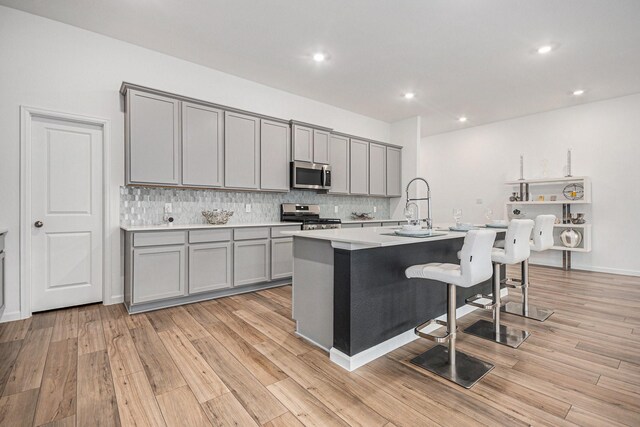 705 Western Fern, League City, TX 77573 - kitchen with appliances with stainless steel finishes, gray cabinets, a sink, a kitchen breakfast bar, and tasteful backsplash