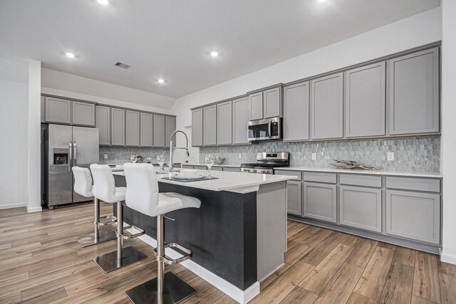 705 Western Fern, League City, TX 77573 - kitchen featuring appliances with stainless steel finishes, gray cabinetry, light wood-type flooring, a kitchen island with sink, and recessed lighting
