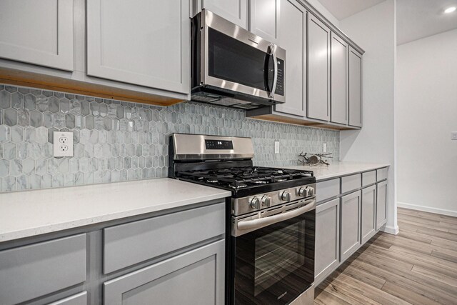 705 Western Fern, League City, TX 77573 - kitchen with stainless steel appliances, gray cabinetry, light countertops, light wood-style flooring, and baseboards
