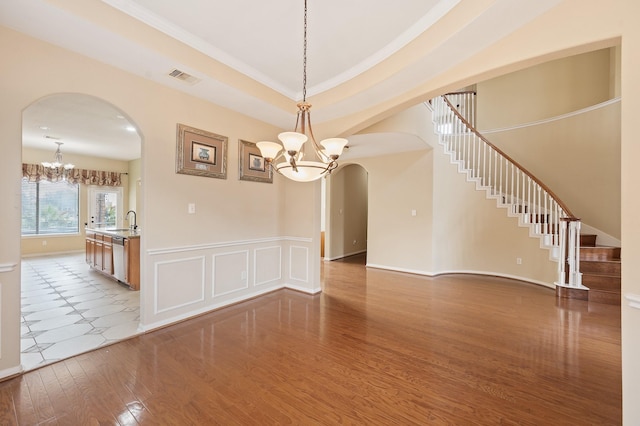 9710 Lansing Meadows Dr, Humble, TX 77396 - unfurnished dining area with a chandelier, arched walkways, wood finished floors, stairway, and crown molding