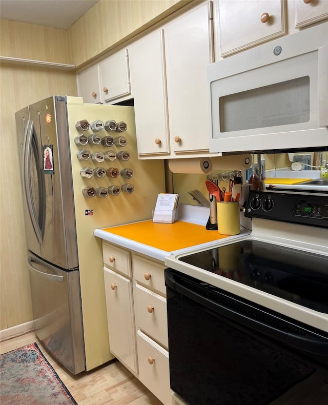7575 Katy Fwy Unit 29, Houston, TX 77024 - kitchen featuring range with electric cooktop, white microwave, light countertops, white cabinetry, and light wood-style flooring