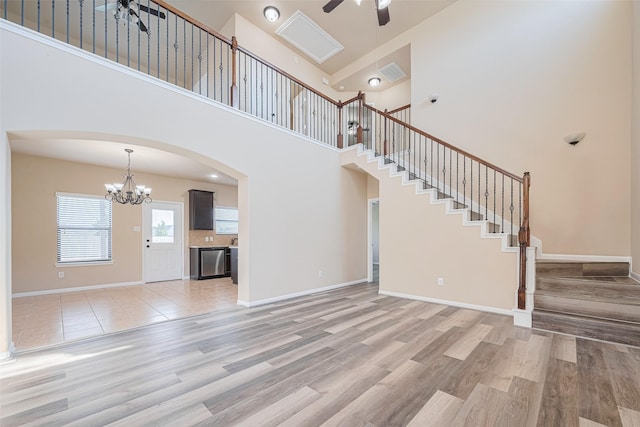 10015 Black Birch Ln, Tomball, TX 77375 - unfurnished living room with ceiling fan, arched walkways, a towering ceiling, a chandelier, and stairs