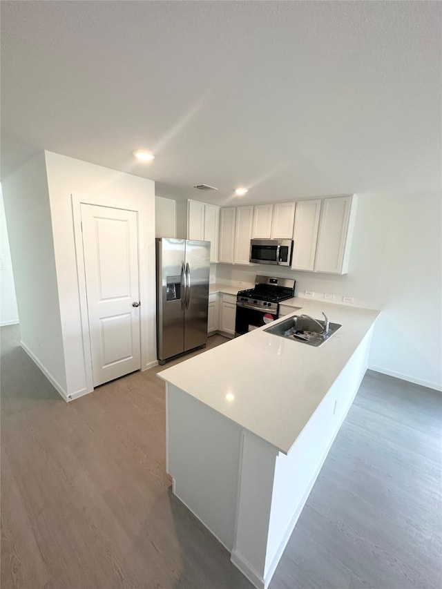 16477 Blossom Grove Dr, Conroe, TX 77303 - kitchen with stainless steel appliances, a sink, a peninsula, baseboards, and wood finished floors
