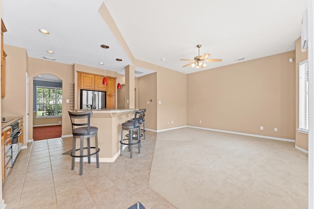 2411 Clippers Sq, Houston, TX 77058 - kitchen featuring stainless steel refrigerator with ice dispenser, arched walkways, a breakfast bar area, ceiling fan, and baseboards