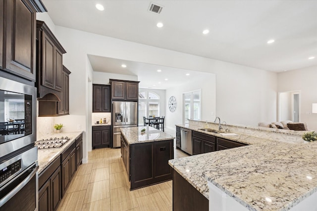 2314 Umber Oaks Ln, Brookshire, TX 77423 - kitchen with appliances with stainless steel finishes, a spacious island, a sink, recessed lighting, and dark brown cabinetry