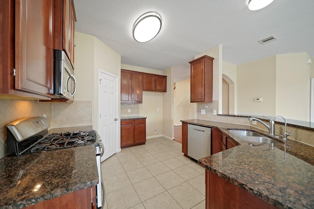 8727 Debbie Terrace Dr, Cypress, TX 77433 - kitchen featuring stainless steel appliances, a sink, dark stone countertops, light tile patterned flooring, and a textured ceiling
