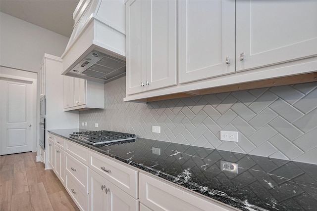 5106 Blooming Hibiscus Ln, Manvel, TX 77578 - kitchen with stainless steel gas cooktop, white cabinetry, custom exhaust hood, dark stone countertops, and tasteful backsplash