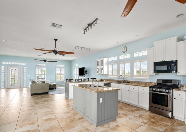 815 5th St, San Leon, TX 77539 - kitchen with black appliances, a sink, ceiling fan, and light stone counters